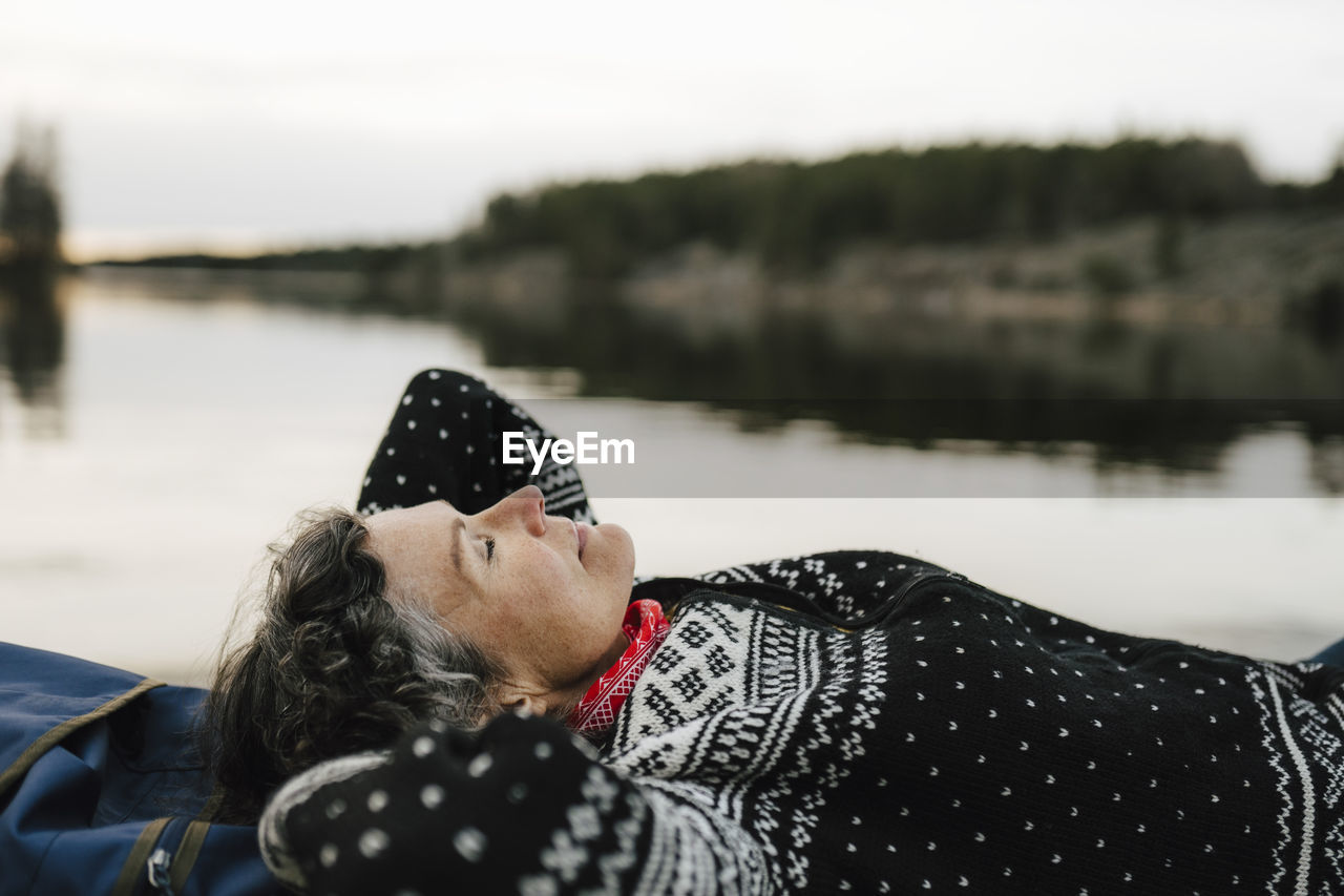 Caucasian female hiker resting by lake during vacation