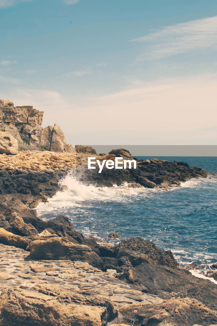 Rock formation on beach against sky