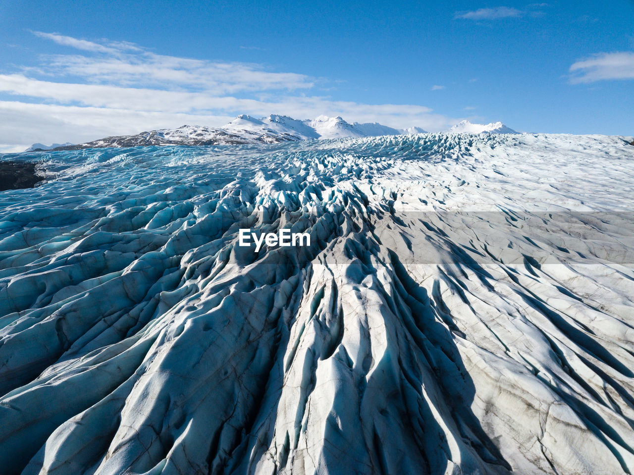AERIAL VIEW OF SNOWCAPPED MOUNTAIN AGAINST BLUE SKY
