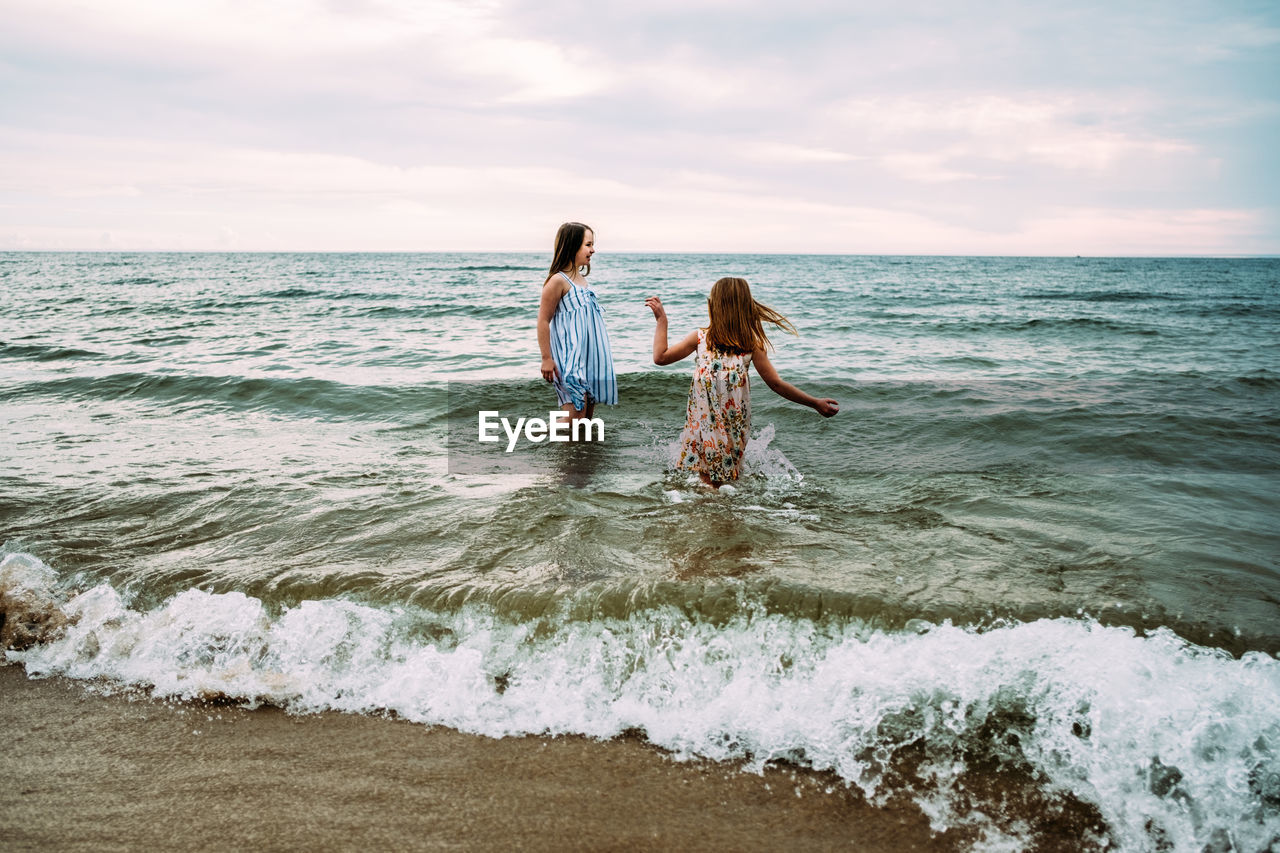 Girls playing fully dressed in lake michigan on summer day