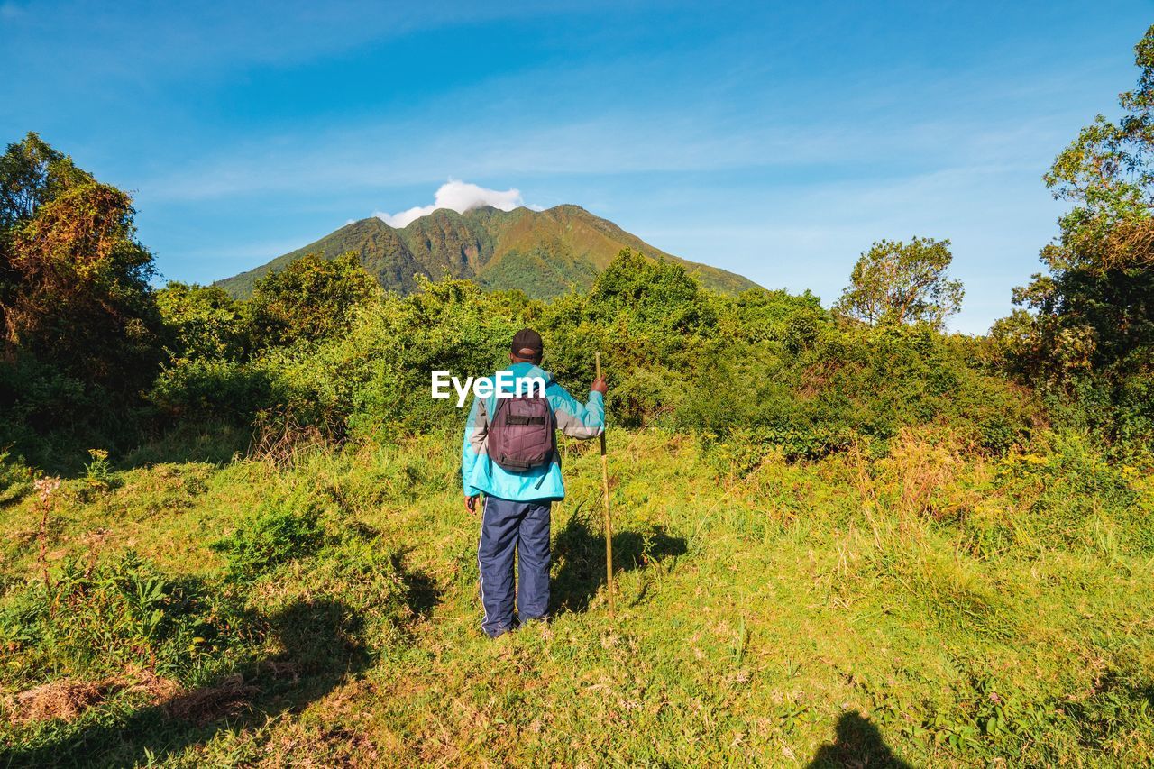 Rear view of a hiker against mount sabyinyo in the mgahinga gorilla national park, virungas, uganda