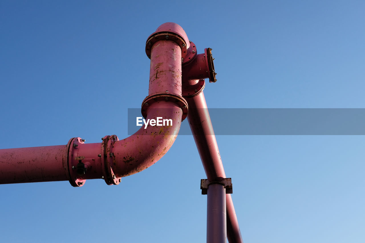 LOW ANGLE VIEW OF PIPE AGAINST BLUE SKY