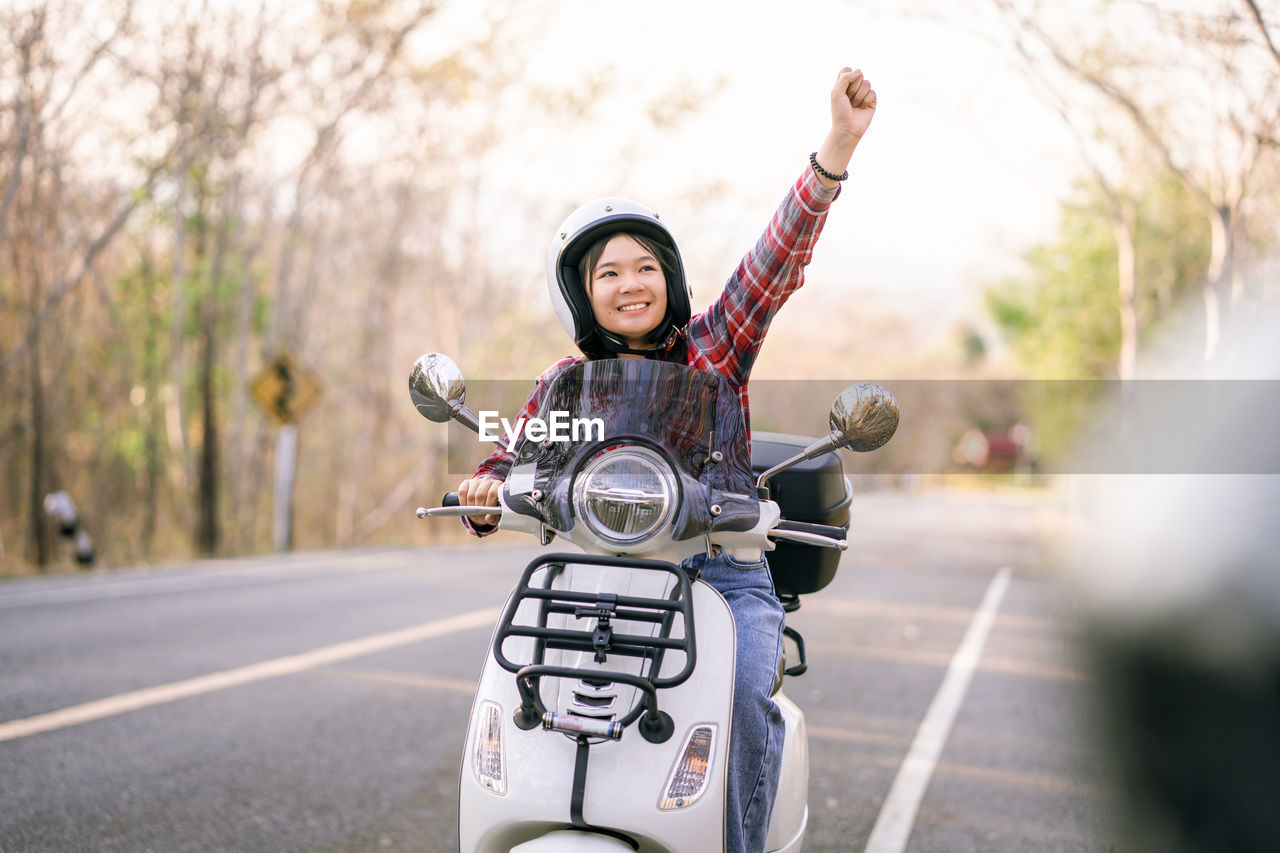 Teenager girl riding motor scooter on road