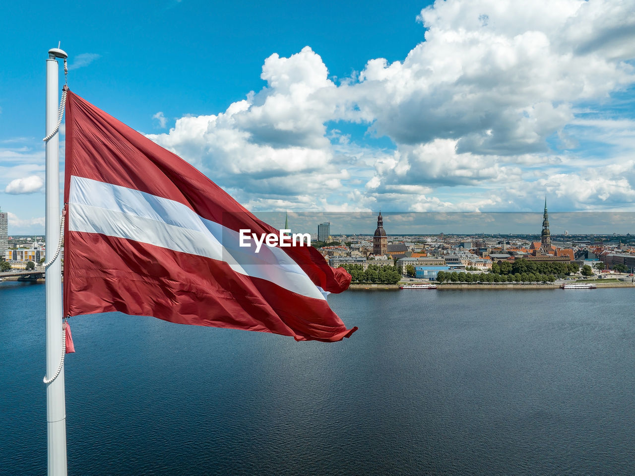 Latvian flag with the dome cathedral and an old town in the background