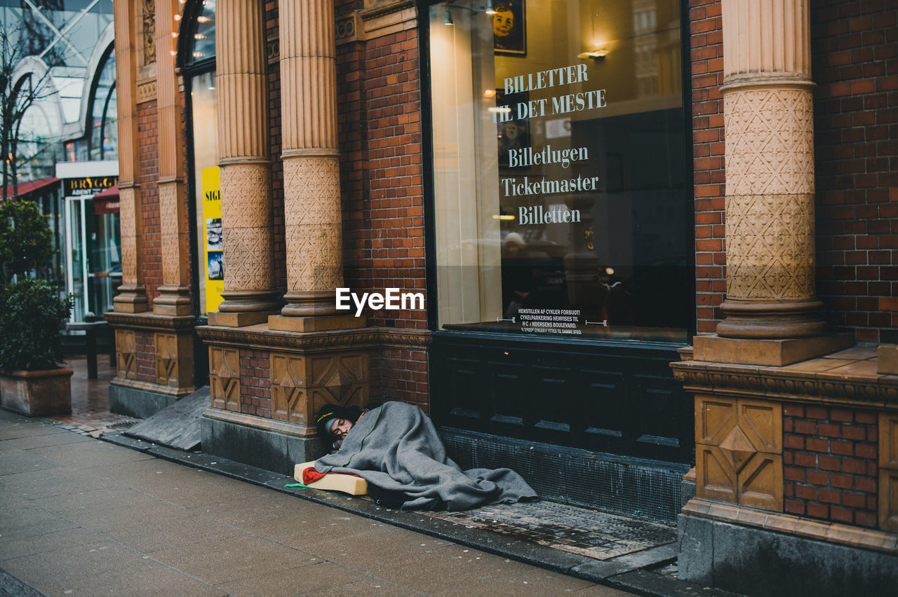 MAN SITTING OUTSIDE BUILDING