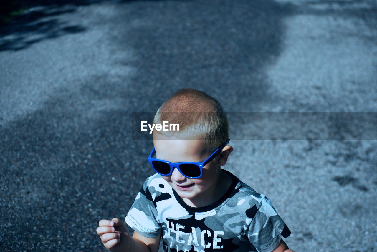 Boy wearing sunglasses while standing on road