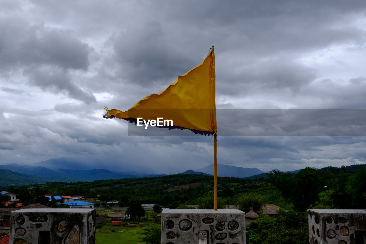 YELLOW FLAG AGAINST CLOUDY SKY