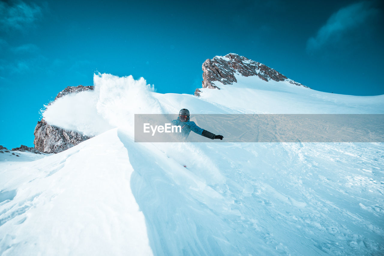 Person snowboarding on snowcapped mountain against sky