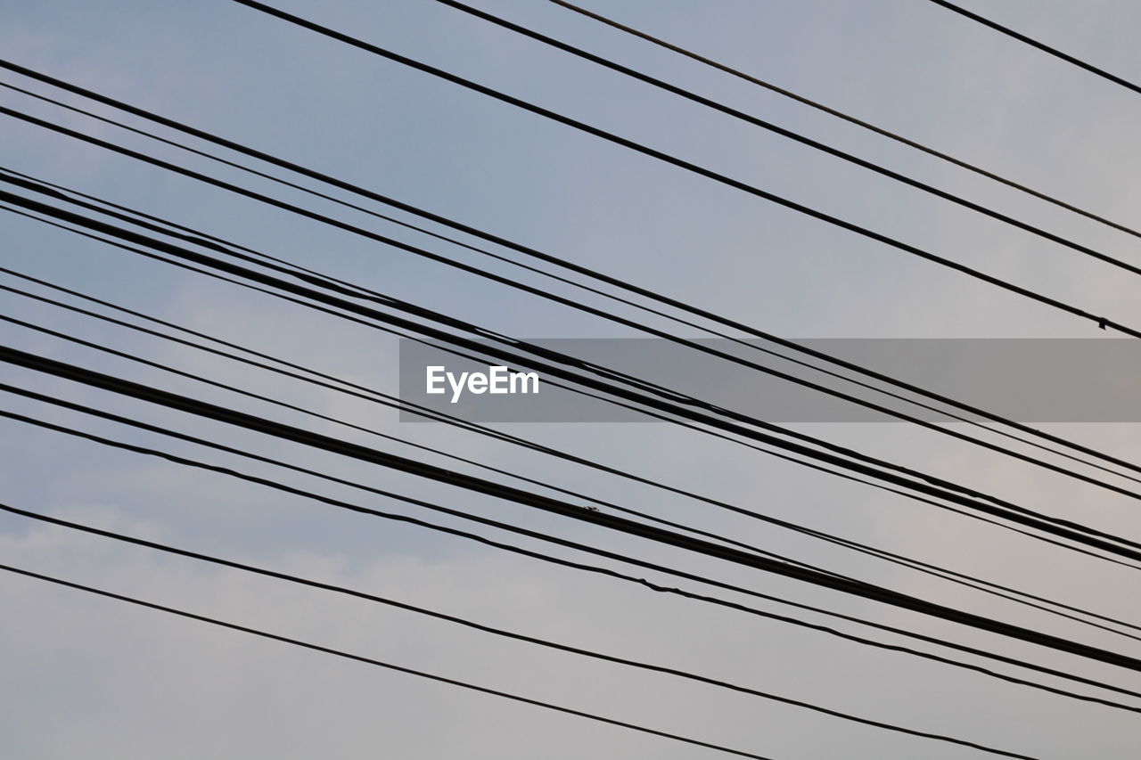 LOW ANGLE VIEW OF POWER CABLES AGAINST SKY