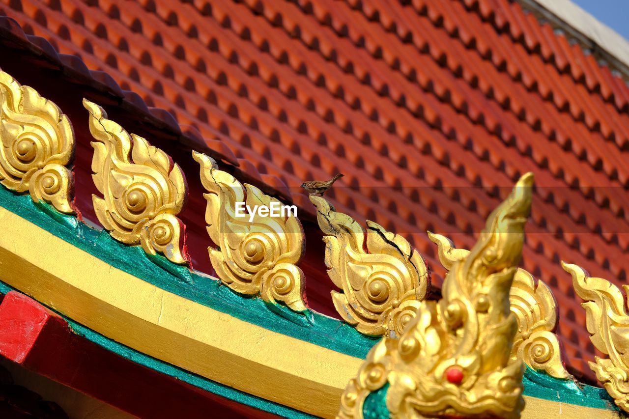 CLOSE-UP OF BUDDHA STATUE AGAINST BUILDING AND WALL