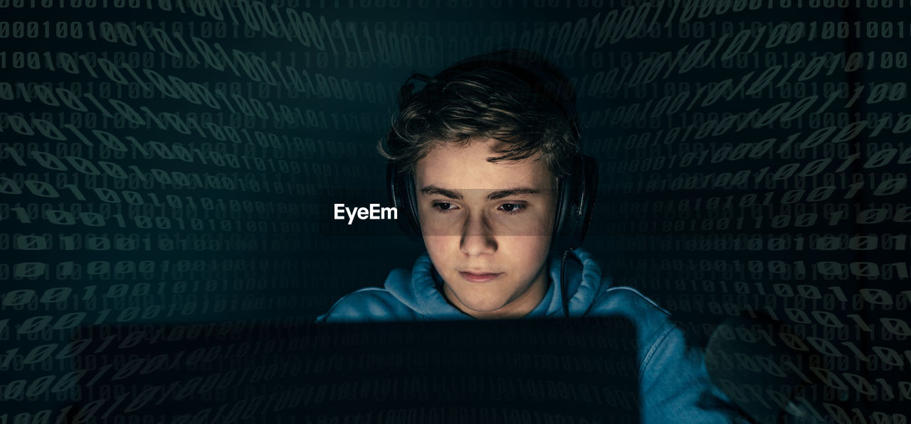 Teenager focused on computer display. green numbers on background. hacker attack,cyber crime concept