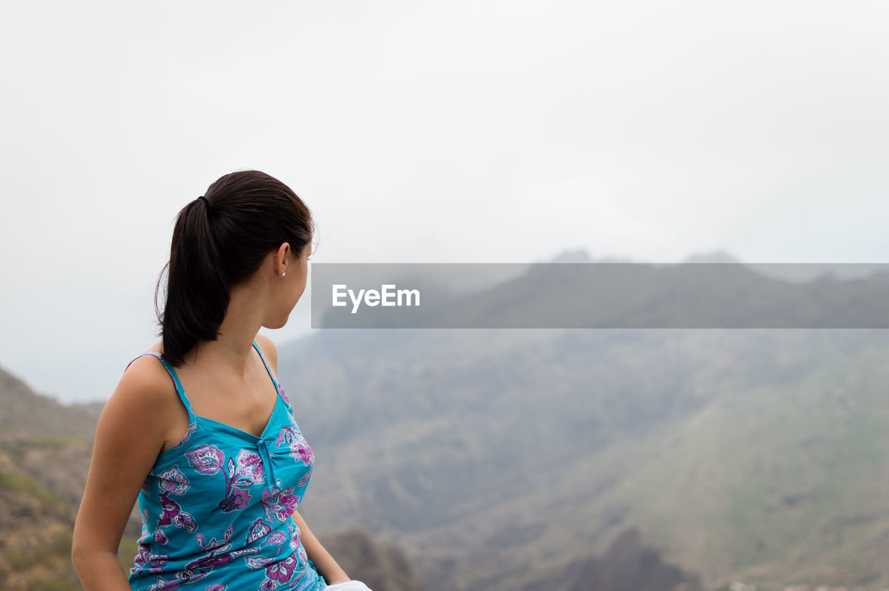 Woman looking at mountains against sky