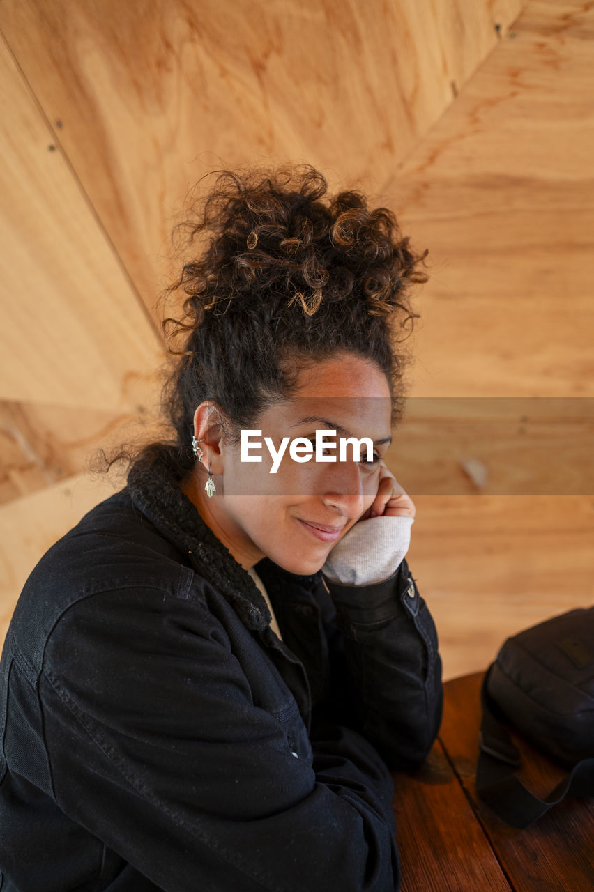 Happy latin woman smiling while sitting indoors.