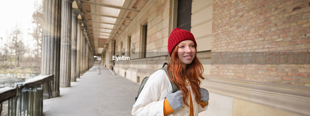 portrait of young woman standing against wall