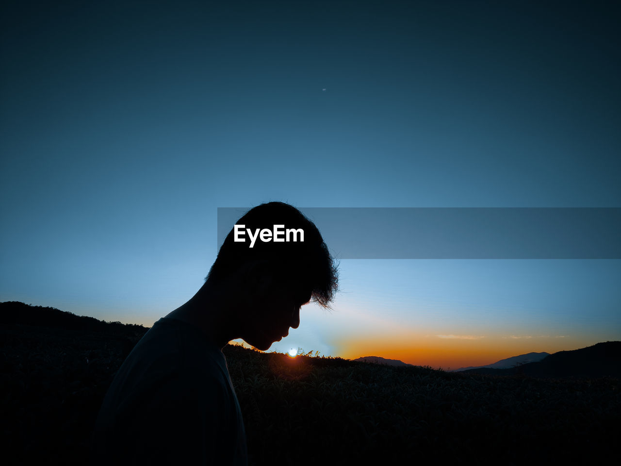 SILHOUETTE MAN STANDING AGAINST BLUE SKY DURING SUNSET