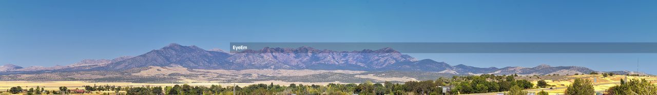 Panoramic view of trees and mountains against blue sky