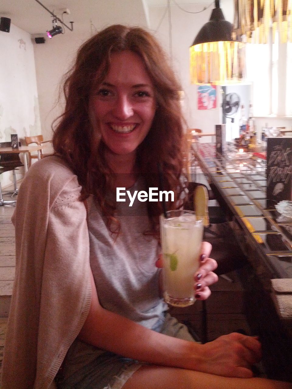 Portrait of a smiling young woman holding drink at restaurant