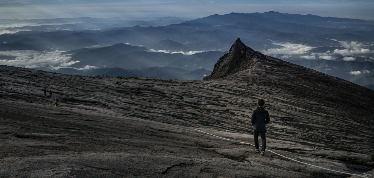 Rear view of man standing on land against sky in kota kinabalu