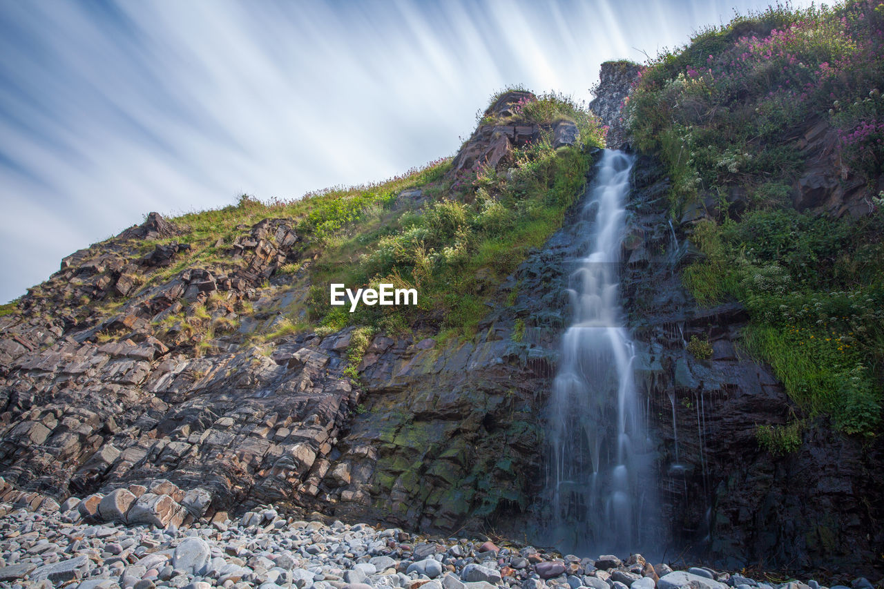 Scenic view of waterfall against sky