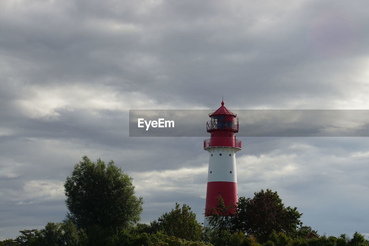 Lighthouse by building against sky