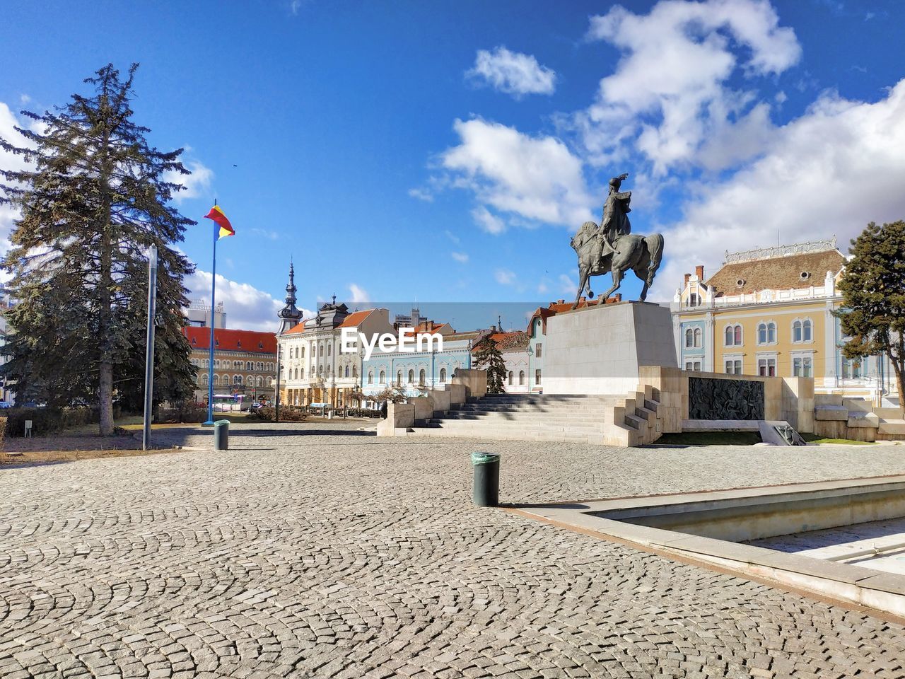 STATUE AMIDST BUILDINGS AGAINST SKY IN CITY