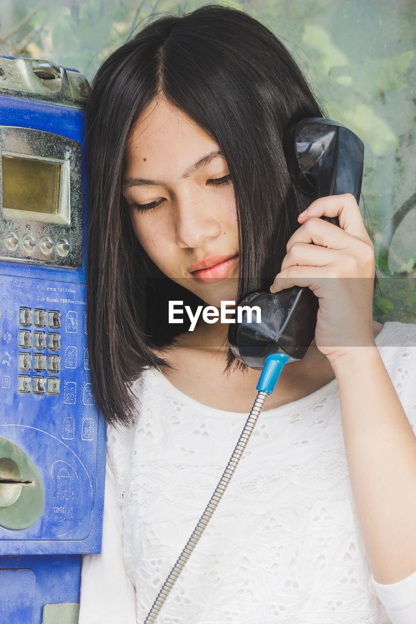 Close up portrait of beautiful girls use classic public phone booths old communication, technology.