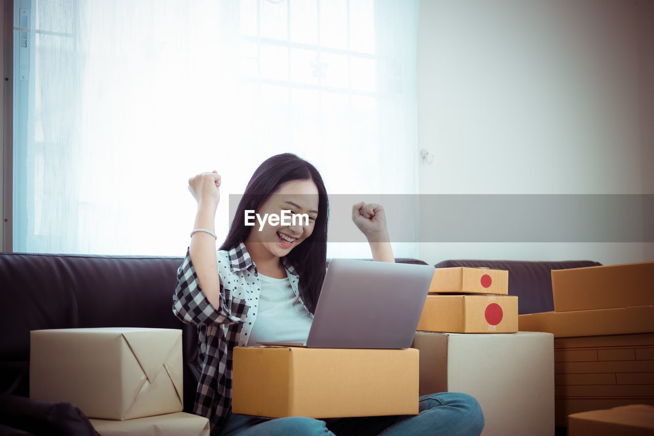 Happy businesswoman looking at laptop while sitting on sofa