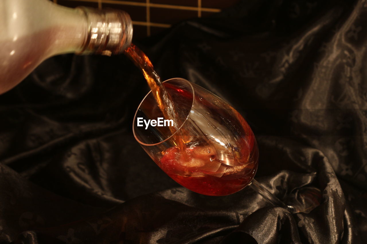 CLOSE-UP OF RED WINE POURING IN GLASS CONTAINER