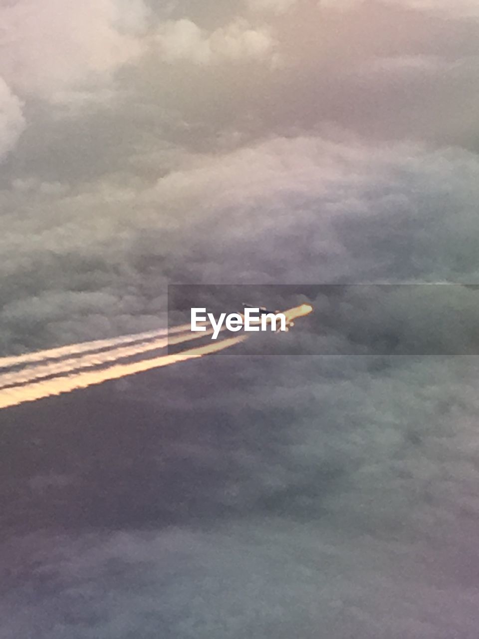 AIRPLANE FLYING OVER CLOUDS AGAINST SKY