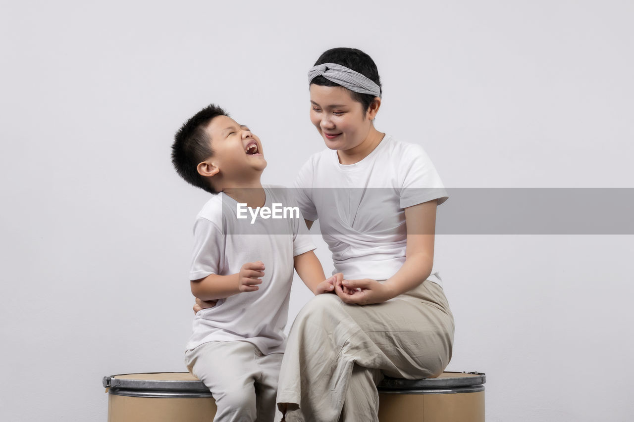 FULL LENGTH OF A BOY SITTING ON WHITE BACKGROUND