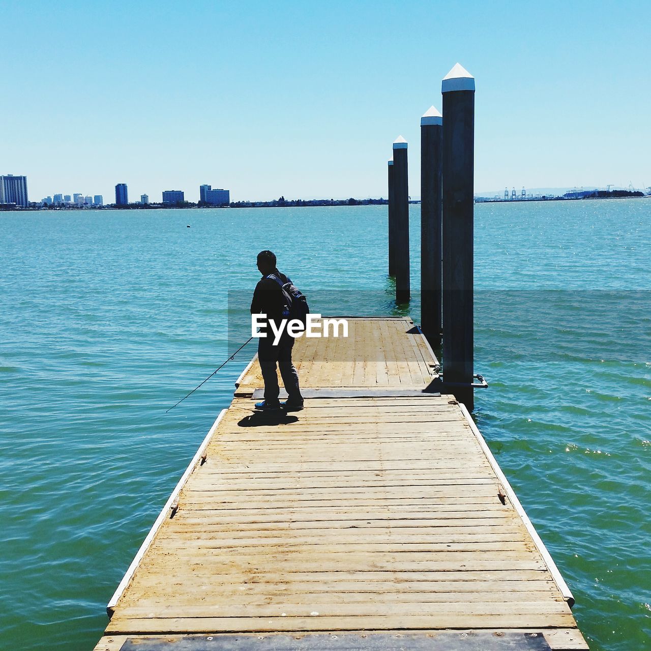 Full length of man fishing by turquoise sea