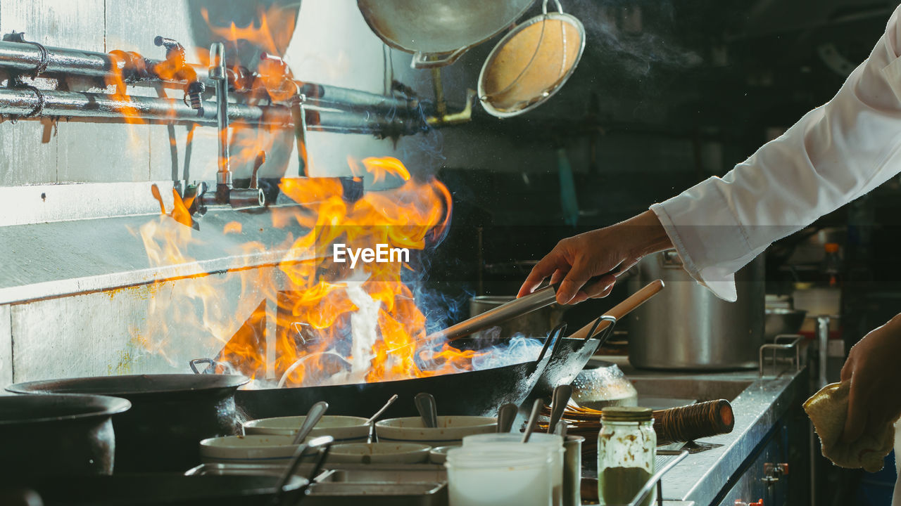 Chef stir fry busy cooking in kitchen. chef stir fry the food in a frying pan