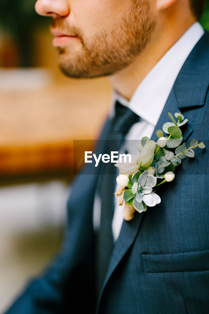 Midsection of man with flower on coat