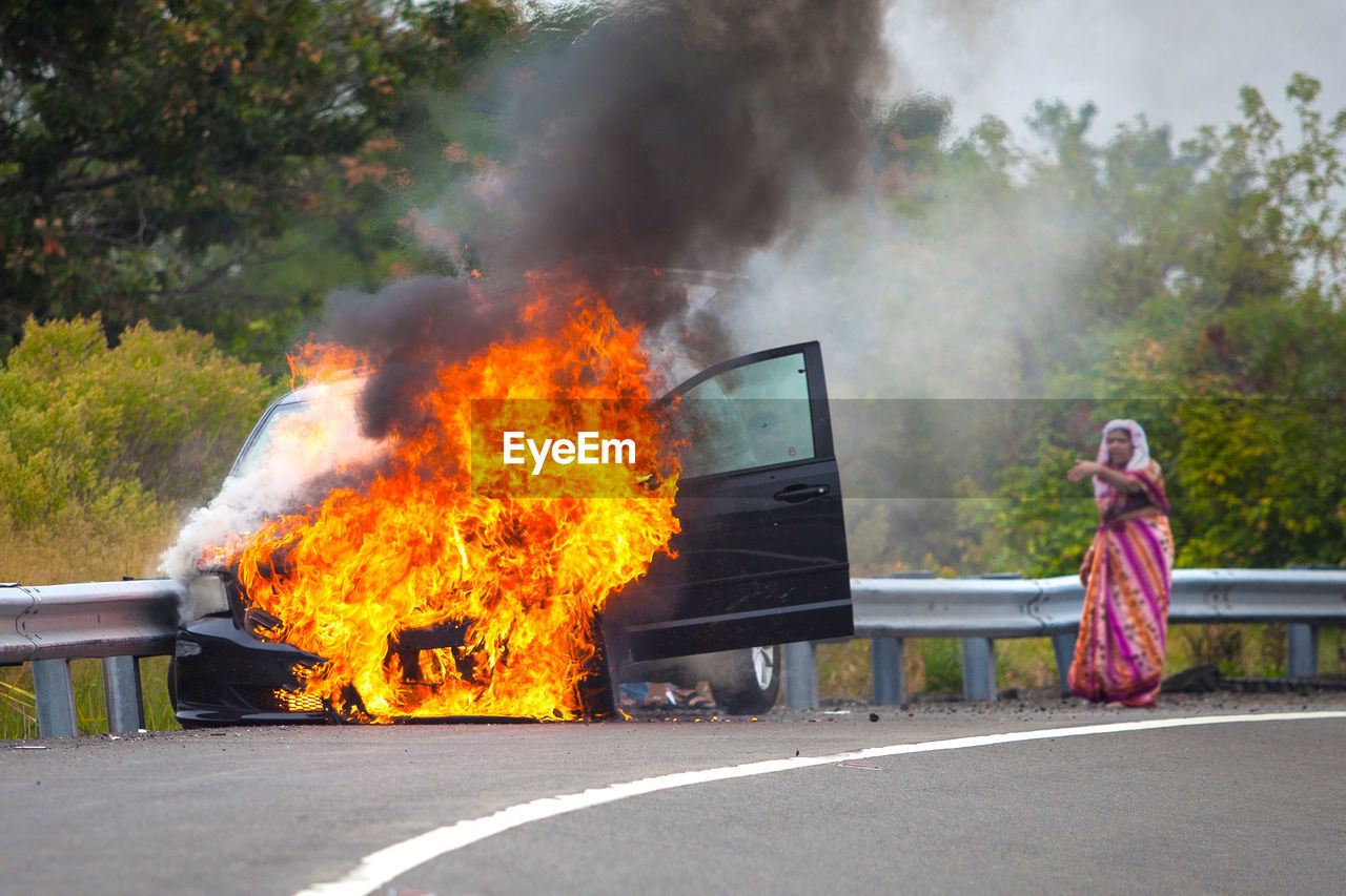 Car on fire with passengers on highway and smoke