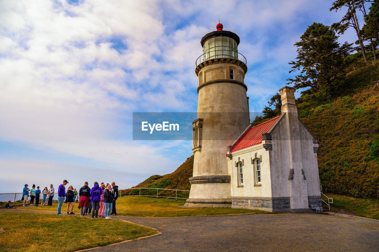 architecture, lighthouse, tower, built structure, sky, building exterior, group of people, building, cloud, nature, travel destinations, travel, history, men, the past, plant, tourism, guidance, large group of people, day, adult, outdoors, landscape, land, grass, water, crowd, women, leisure activity, tree