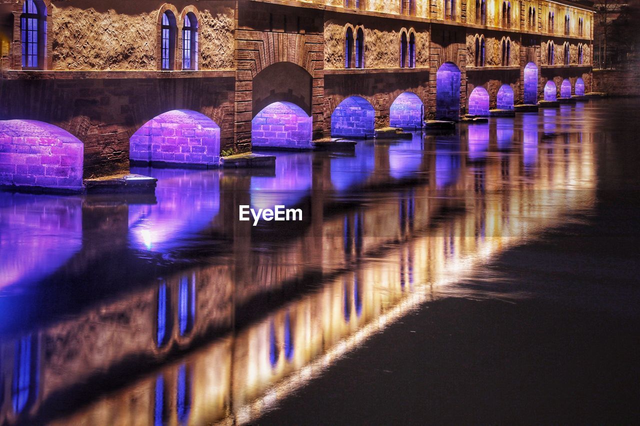 Illuminated bridge over river at night