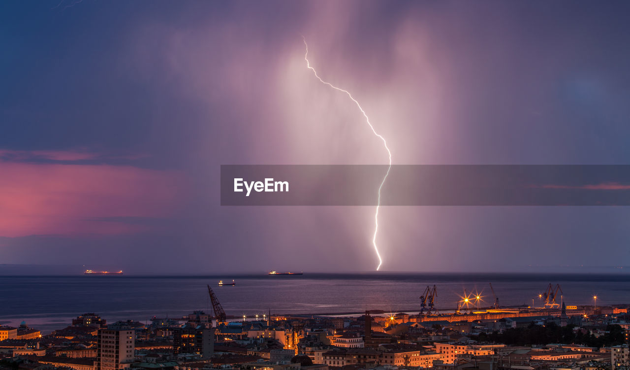 PANORAMIC VIEW OF LIGHTNING OVER SEA AGAINST STORM CLOUDS