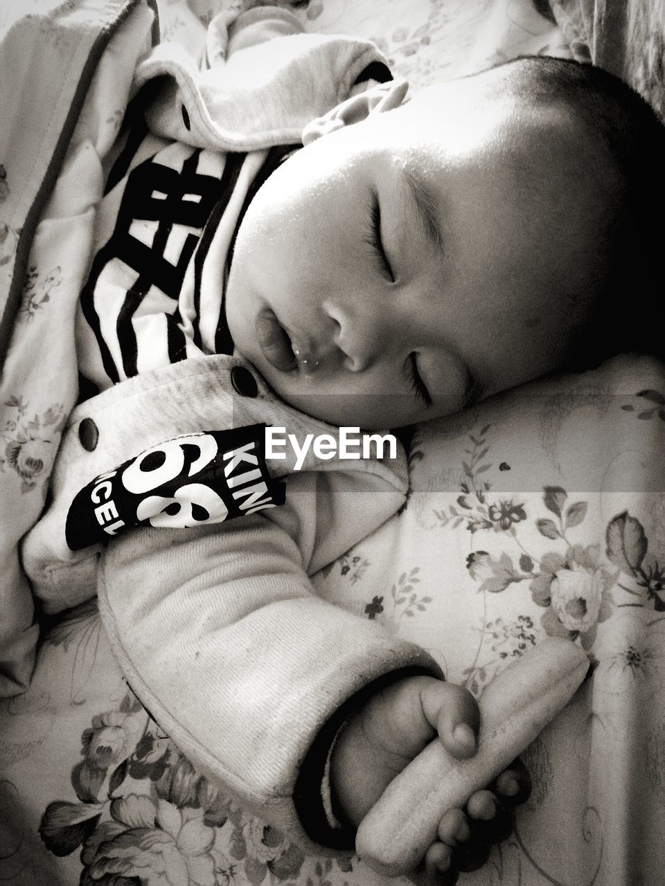 High angle view of baby holding toy while sleeping on bed at home