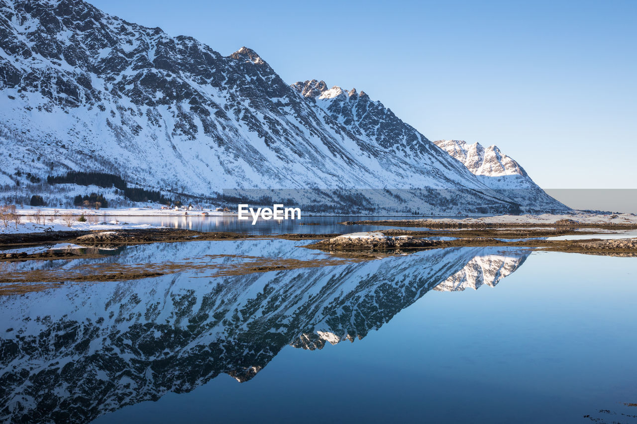 Frozen lake by snowcapped mountains against sky