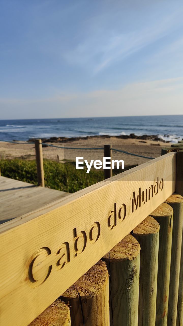 sea, text, water, western script, horizon over water, beach, sky, communication, wood, horizon, vacation, land, nature, coast, no people, sign, day, ocean, scenics - nature, sand, tranquility, tranquil scene, beauty in nature, outdoors, information sign, railing, shore