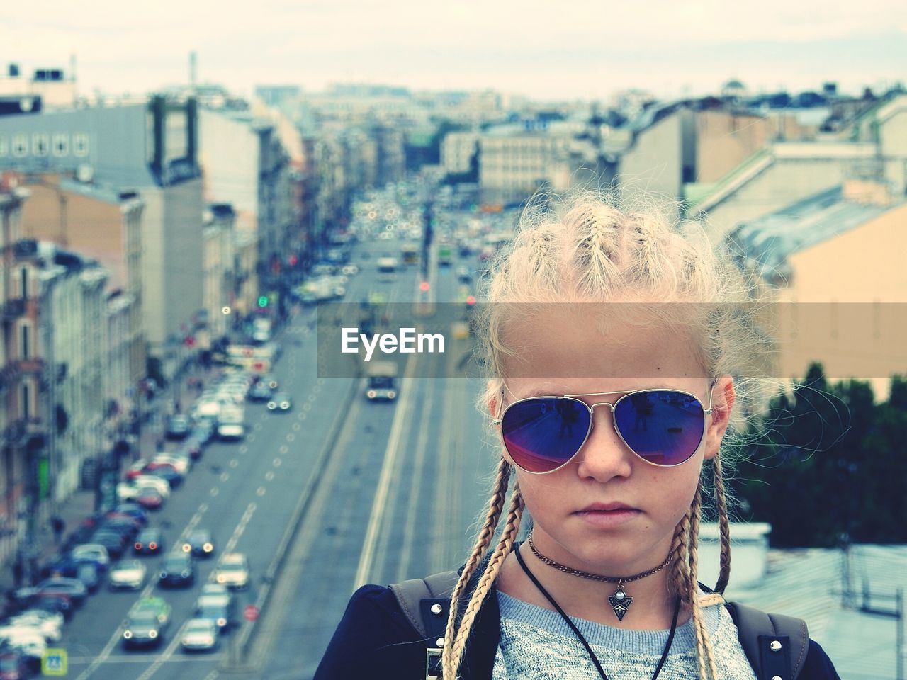 Portrait of girl wearing sunglasses against cityscape