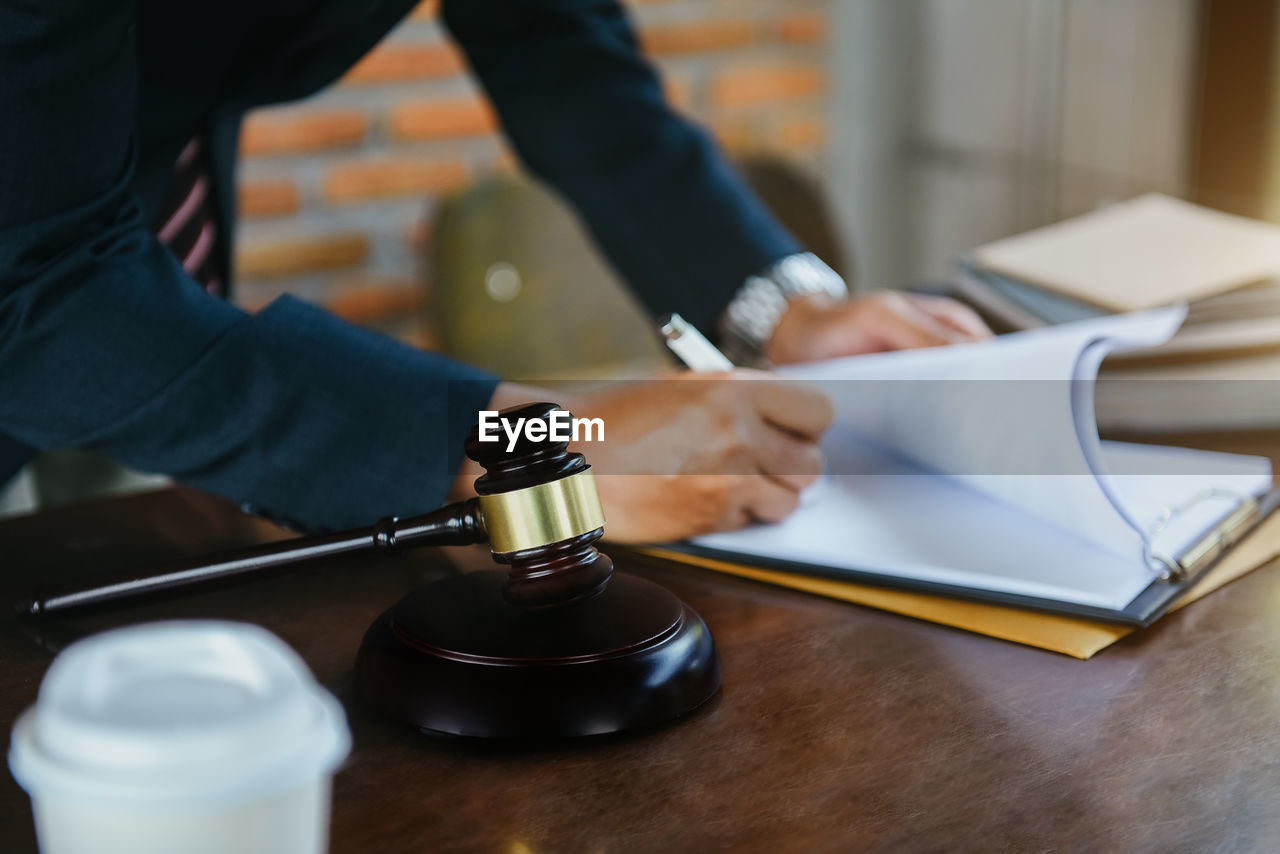 cropped hand of lawyer working at table