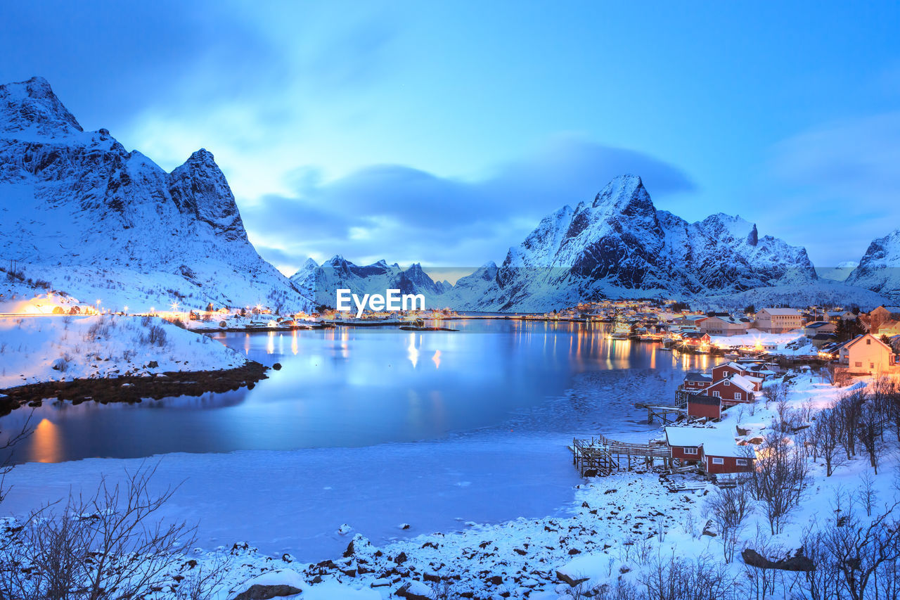 Scenic view of lake and snowcapped mountains against sky at lofoten during dusk