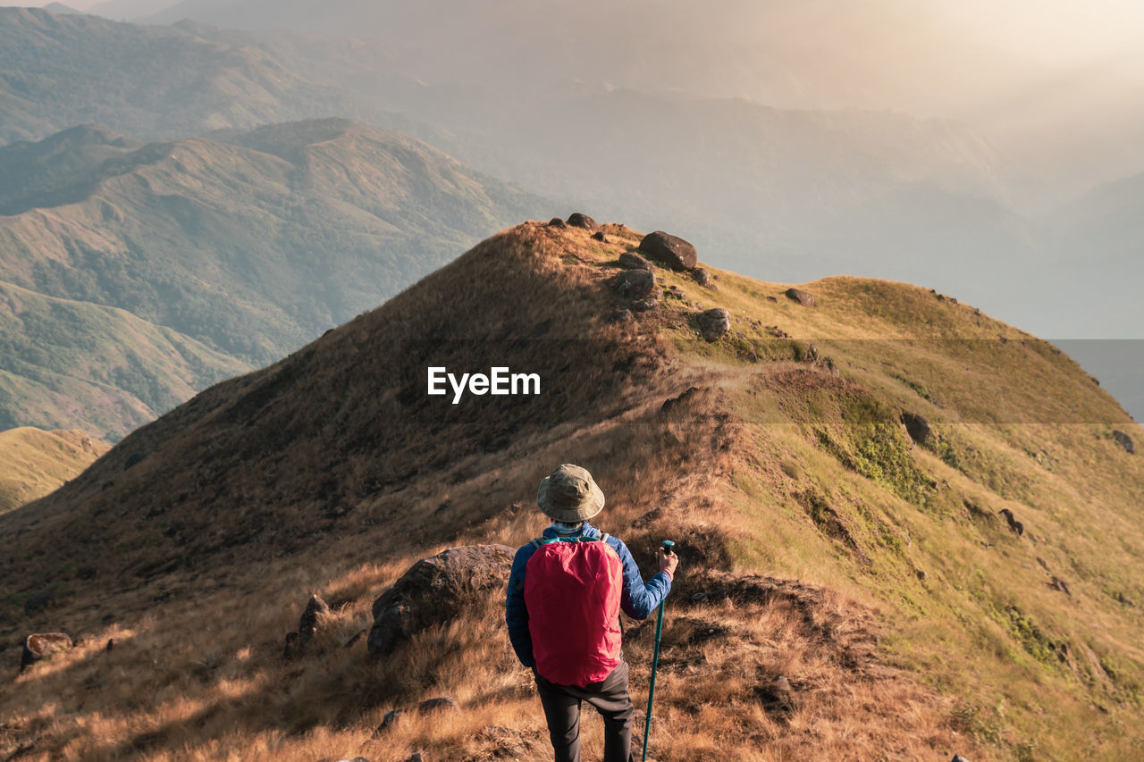 Rear view of backpacker looking at landscape while standing on mountain