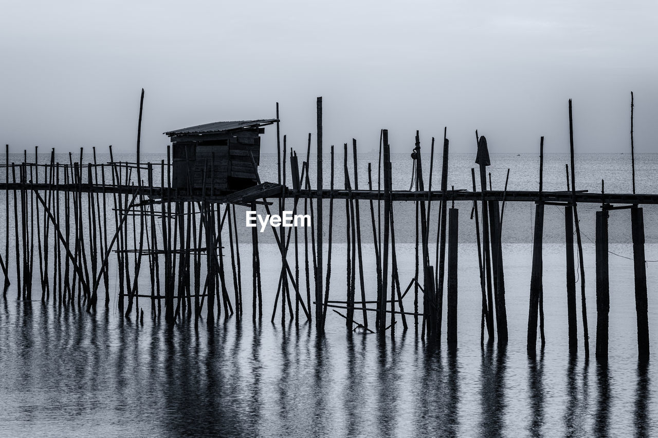 WOODEN POSTS ON PIER AGAINST SKY