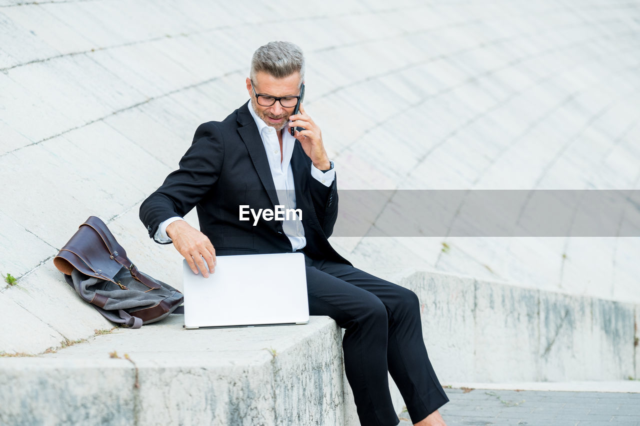 Businessman using mobile phone while sitting outdoors