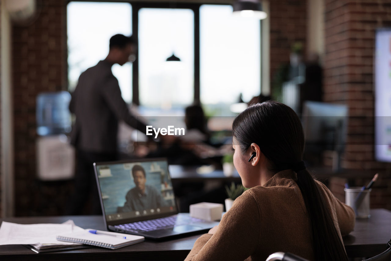 Rear view of man using laptop at office