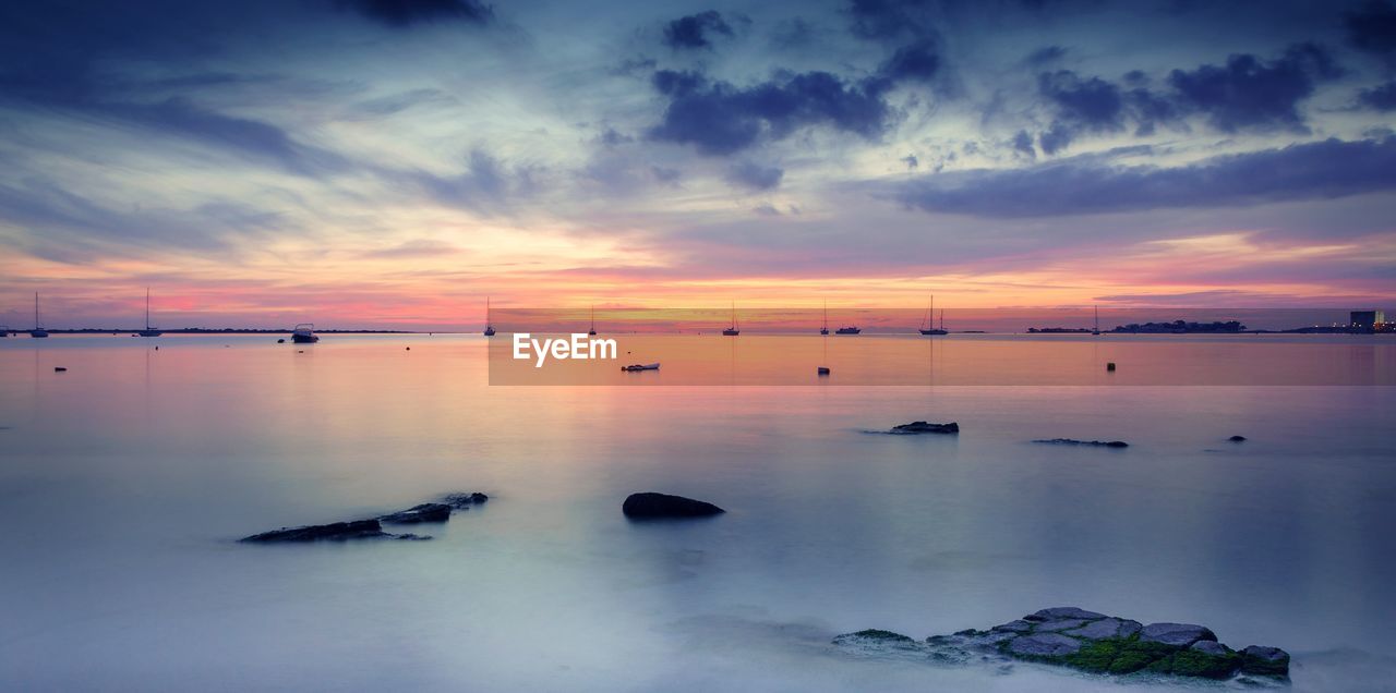 Scenic view of sea against cloudy sky at sunset