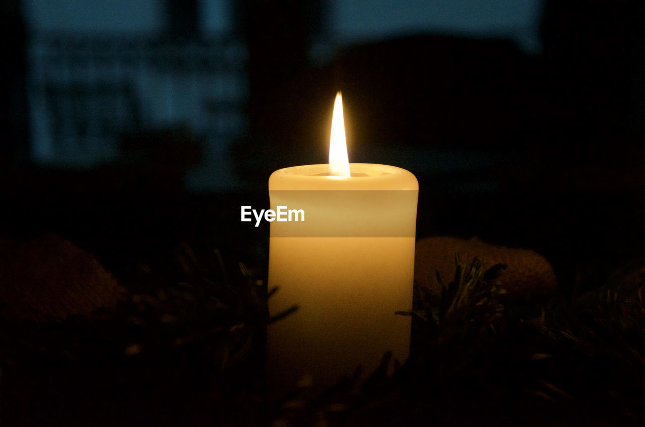 Close-up of lit candle in darkroom