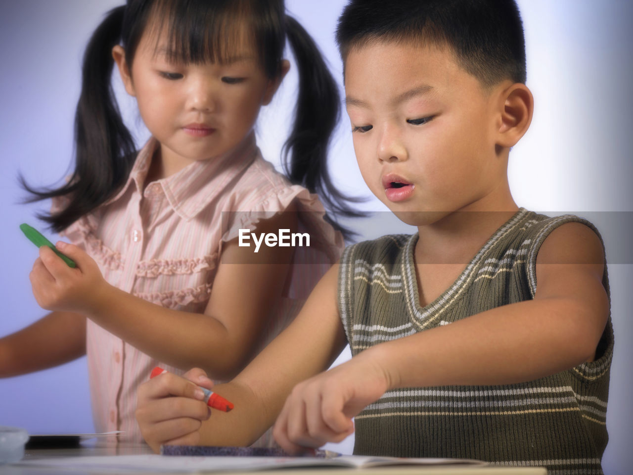 Close-up of boy with sister holding crayon